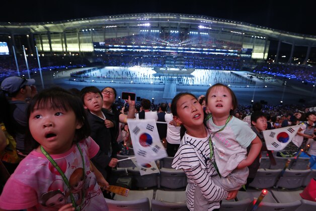 Young visitors watch video screens during the opening ceremony for the 17th Asian Games in Incheon, South Korea, Friday, Sept. 19, 2014. (AP Photo/Kin Cheung)