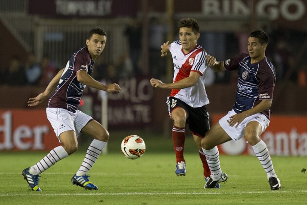 River Plate's Matias Kranevitter, center, vies for the ball with Diego Gonzalez, right, and Maximiliano Velazquez, left, of Argentina's Lanus during a Copa Sudamericana soccer match on Tuesday, Oct. 29, 2013, in Buenos Aires, Argentina. (AP Photo/Eduardo Di Baia)