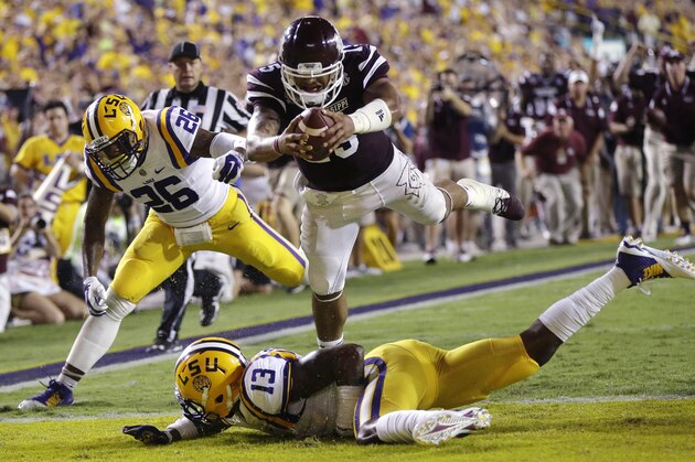 Mississippi State quarterback Dak Prescott (15) dives into the end zone over LSU cornerback Dwayne Thomas (13) and safety Ronald Martin (26) on a 56 yard touchdown run in the second half of an NCAA college football game in Baton Rouge, La., Saturday, Sept. 20, 2014. (AP Photo/Gerald Herbert)