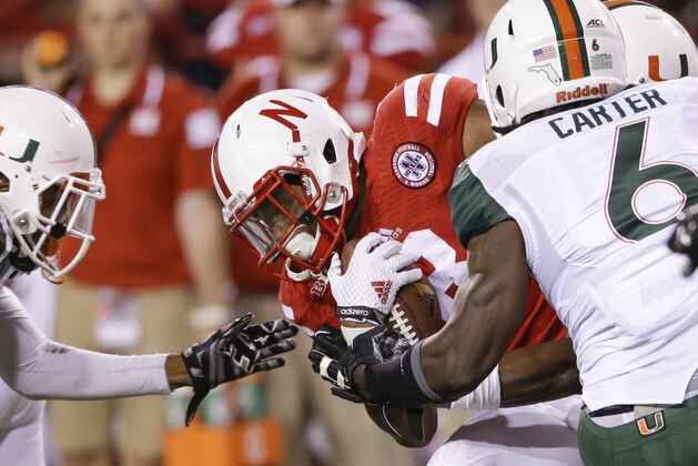 Nebraska running back Ameer Abdullah, center, is tackled by Miami defensive back Corn Elder, left, and safety Jamal Carter (6) in the second half of an NCAA college football game in Lincoln, Neb., Saturday, Sept. 20, 2014. Nebraska won 41-31. (AP Photo/Nati Harnik)