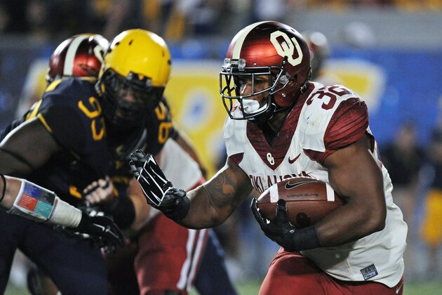 Oklahoma's Samaje Perine (32) reaches to stiff-arm a West Virginia defender during the fourth quarter of an NCAA college football game in Morgantown, W.Va., Saturday, Sept. 20, 2014. (AP Photo/Tyler Evert)