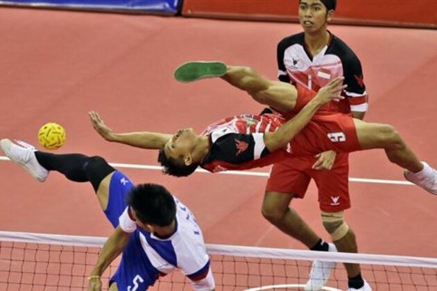 CORRECTS NAME OF MATCH TO SEPAK TAKRAW - Indonesia's Nofrizal, right, flies in the air as he returns a ball against Laos' Noum Souvannalisth and his team mate Daovy during their Men's Doubles Preliminary Group B sepak takraw match at the 17th Asian Games in Incheon, South Korea, Saturday, Sept. 20, 2014. (AP Photo/Dita Alangkara)