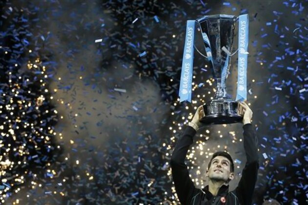 Novak Djokovic of Serbia holds up the ATP World Tour Finals tennis trophy as he poses for photographers after defeating Rafael Nadal of Spain at the O2 Arena in London, Monday, Nov. 11, 2013. (AP Photo/Kirsty Wigglesworth)