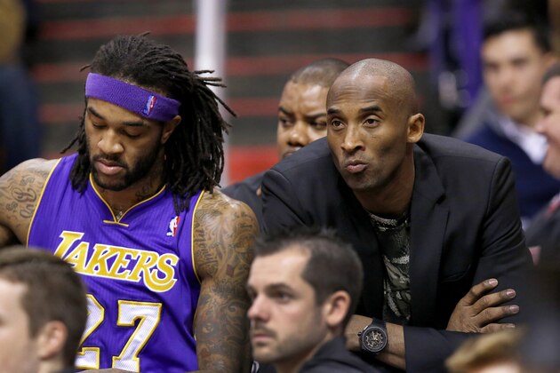 Injjured Los Angeles Lakers player Kobe Bryant, right, sits on the end of the team bench next to Jordan Hill, left, during the first half of an NBA basketball game against the Phoenix Suns on Wednesday, Jan. 15, 2014, in Phoenix. (AP Photo/Ross D. Franklin)