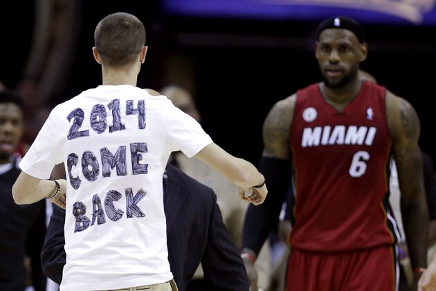 A fan runs out on the court towards Miami Heat's LeBron James during the fourth quarter of an NBA basketball game against the Cleveland Cavaliers on Wednesday, March 20, 2013, in Cleveland. Miami won 98-95. (AP Photo/Tony Dejak)