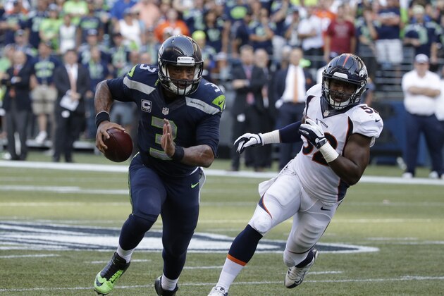 Seattle Seahawks quarterback Russell Wilson (3) scrambles with the football as Denver Broncos outside linebacker Corey Nelson pursues at right, in the second half of an NFL football game, Sunday, Sept. 21, 2014, in Seattle. (AP Photo/Elaine Thompson)