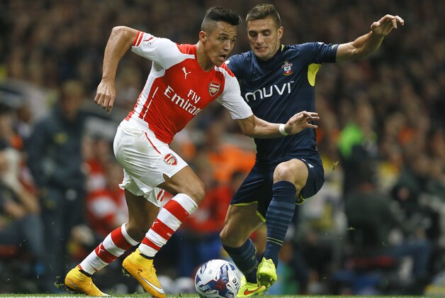 Arsenal's Alexis Sanchez, left, vies for the ball with Southampton's Dusan Tadic during the English League Cup soccer match between Arsenal and Southampton at Emirates Stadium in London, Tuesday, Sept. 23, 2014. (AP Photo/Kirsty Wigglesworth)