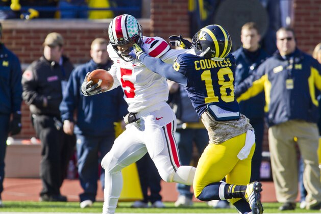 Ohio State quarterback Braxton Miller (5) tries to keep back Michigan defensive back Blake Countess (18), face mask being pulled, as he rushes for a touchdown in the first quarter of an NCAA college football game in Ann Arbor, Mich., Saturday, Nov. 30, 2013. (AP Photo/Tony Ding)
