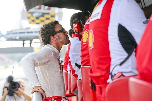 Ferrari driver Fernando Alonso, of Spain, watches a screen in the pit lane after failing to complete the Italian Formula One Grand Prix at the Monza racetrack, in Monza, Italy, Sunday, Sept. 7, 2014. (AP Photo/Srdjan Suki/EPA POOL)