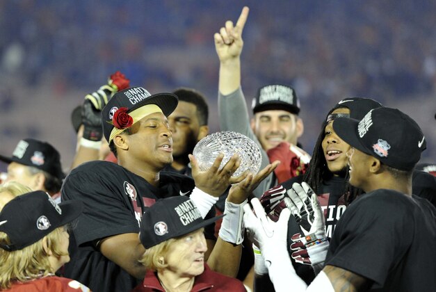 Jan 6, 2014; Pasadena, CA, USA; Florida State Seminoles quarterback Jameis Winston (left) hands the Coaches Trophy to defensive back P.J. Williams (right)  after the 2014 BCS National Championship game against the Auburn Tigers at the Rose Bowl.  Mandatory Credit: Kirby Lee-USA TODAY Sports
