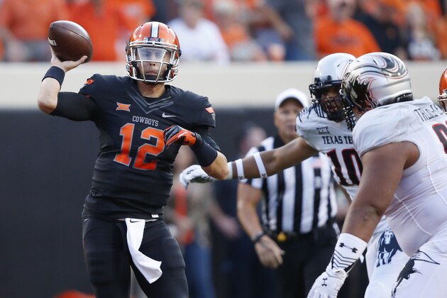 Oklahoma State quarterback Daxx Garman (12) passes under pressure from Texas Tech defenders in the first quarter of an NCAA college football game in Stillwater, Okla., Thursday, Sept. 25, 2014. (AP Photo/Sue Ogrocki)