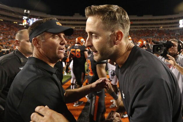 Oklahoma State head coach Mike Gundy, left, and Texas Tech head coach Kliff Kingsbury, right, meet at midfield following an NCAA college football game in Stillwater, Okla., Thursday, Sept. 25, 2014. Oklahoma State won 45-35. (AP Photo/Sue Ogrocki)