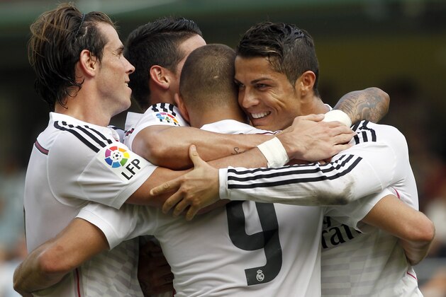 Real Madrid's Cristiano Ronaldo, from Portugal celebrates, right, with Karim Benzema, from France, center, and teammates after scoring against Villarreal during a Spanish La Liga soccer match at the Madrigal stadium in Villarreal, Spain, on Saturday, Sept. 27, 2014.(AP Photo/Alberto Saiz)