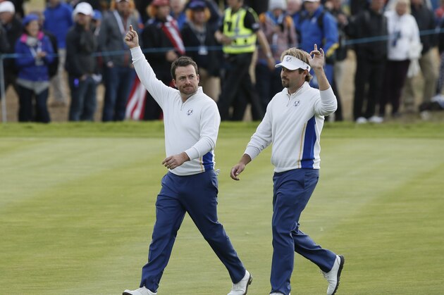 Europe's Graeme McDowell, left, and Victor Dubuisson wave to the crowd as they walk along the 10th fairway during the foursomes match on the second day of the Ryder Cup golf tournament at Gleneagles, Scotland, Saturday, Sept. 27, 2014. (AP Photo/Alastair Grant)