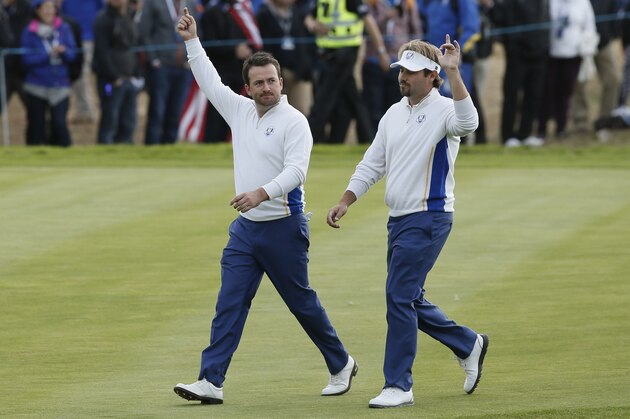 Europe's Graeme McDowell, left, and Victor Dubuisson wave to the crowd as they walk along the 10th fairway during the foursomes match on the second day of the Ryder Cup golf tournament at Gleneagles, Scotland, Saturday, Sept. 27, 2014. (AP Photo/Alastair Grant)