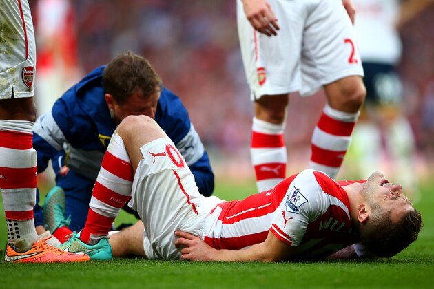 LONDON, ENGLAND - SEPTEMBER 27:  Jack Wilshere of Arsenal grimaces as he receives treatment for an injury on the field during the Barclays Premier League match between Arsenal and Tottenham Hotspur at Emirates Stadium on September 27, 2014 in London, England.  (Photo by Paul Gilham/Getty Images)