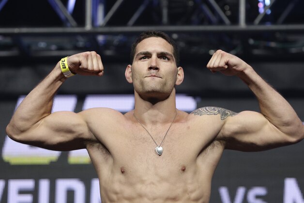 Chris Weidman poses on the scale during a weigh-in for the UFC 175 mixed martial arts event at the Mandalay Bay, Friday, July 4, 2014, in Las Vegas. Weidman is scheduled to fight Lyoto Machida in a middleweight title bout on Saturday in Las Vegas. (AP Photo/John Locher)