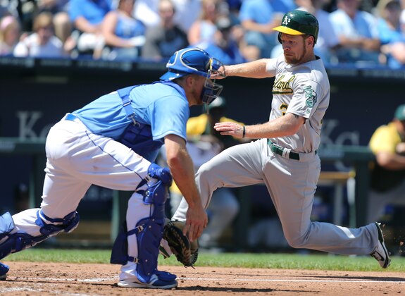 Oakland Athletics' Brandon Moss slides into home to score past Kansas City Royals catcher  Erik Kratz in the fourth inning during a baseball game Thursday, Aug. 14, 2014, in Kansas City, Mo. Kratz scored from third on an Alberto Callaspo sacrifice fly. (AP Photo/Ed Zurga)