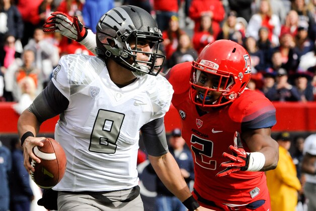 Nov 23, 2013; Tucson, AZ, USA; Oregon Ducks quarterback Marcus Mariota (8) runs the ball under pressure from Arizona Wildcats linebacker Marquis Flowers (2) during the first quarter at Arizona Stadium. Arizona beat Oregon 42-16. Mandatory Credit: Casey Sapio-USA TODAY Sports