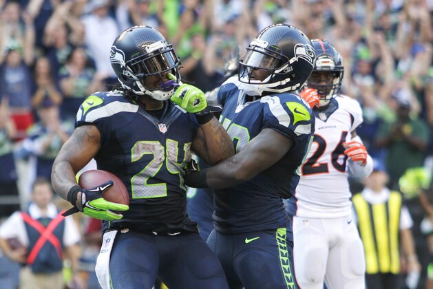 Seattle Seahawks running back Marshawn Lynch (24) celebrates with Derrick Coleman after Lynch scored the game-winning touchdown in overtime of an NFL football game against the Denver Broncos, Sunday, Sept. 21, 2014, in Seattle. The Seahawks won 26-20. (AP Photo/John Froschauer)