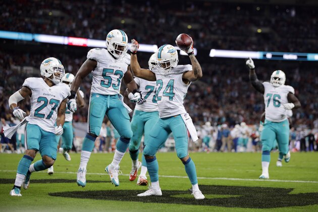 Miami Dolphins' Cortland Finnegan (24) celebrates with teammates after recovering a fumbled snap for a touchdown during the second half of an NFL football game against the Oakland Raiders, Sunday, Sept. 28, 2014, at Wembley Stadium in London. (AP Photo/Lefteris Pitarakis)