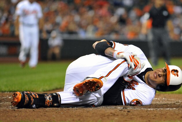 Aug 11, 2014; Baltimore, MD, USA; Baltimore Orioles third baseman Manny Machado (13) goes down with a knee injury after striking out in the third inning against the New York Yankees at Oriole Park at Camden Yards. Mandatory Credit: Joy R. Absalon-USA TODAY Sports