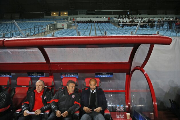 Bayern's head coach Pep Guardiola, right, sits in the dugout as the empty stadium is seen in the background during the Group E Champions League match between CSKA Moscow and Bayern Munich at Arena Khimki stadium in Moscow, Russia, Tuesday Sept. 30, 2014. CSKA were sanctioned by governing body UEFA after the behaviour of their fans during group stage matches against Manchester City and Czech club Viktoria Plzen last season. (AP Photo/Pavel Golovkin)