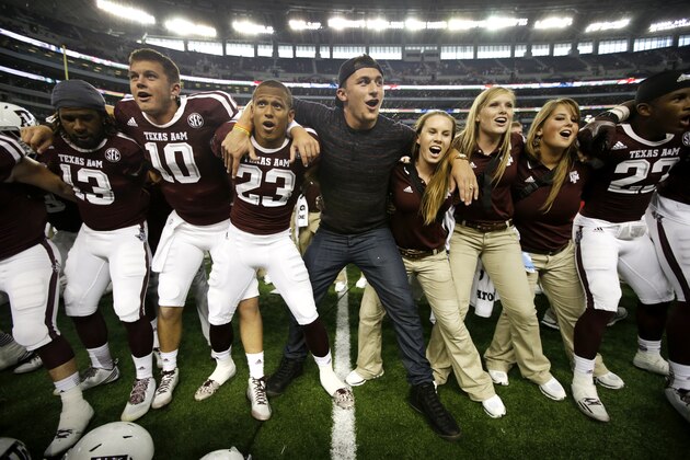 Cleveland Browns quarterback and former Texas A&M quarterback Johnny Manziel, center, joins the team and staff as they sing the Aggie War Hymn after the Aggies 35-28 overtime win against Arkansas in an NCAA college football game, Saturday, Sept. 27, 2014, in Arlington, Texas. (AP Photo/Tony Gutierrez)