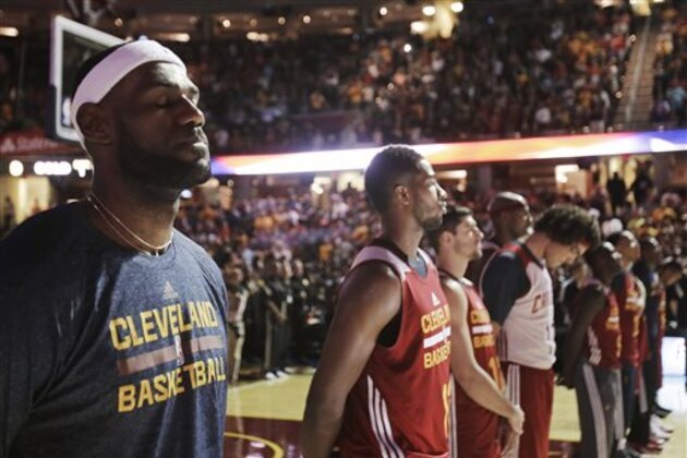 Cleveland Cavaliers' LeBron James, left, stands during the national anthem before the NBA basketball team's scrimmage Wednesday, Oct. 1, 2014, in Cleveland. (AP Photo/Tony Dejak)