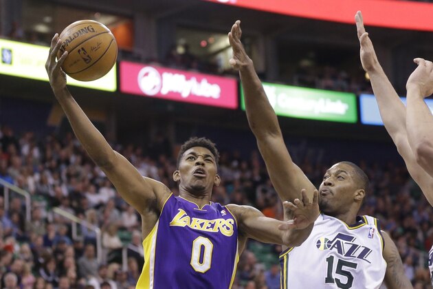Los Angeles Nick Young (0) lays the ball as Utah Jazz's center Derrick Favors (15) defends in the second quarter during an NBA basketball game Monday, April 14, 2014, in Salt Lake City, Utah. (AP Photo/Rick Bowmer)