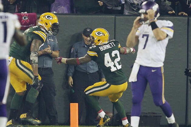 Green Bay Packers' Julius Peppers is congratulated by teammate Morgan Burnett (42) as Minnesota Vikings quarterback Christian Ponder walks off the field after Peppers intercepted a pass and returned it 49-yards for a touchdown  during the first half of an NFL football game against the Minnesota Vikings Thursday, Oct. 2, 2014, in Green Bay, Wis. (AP Photo/Tom Lynn)