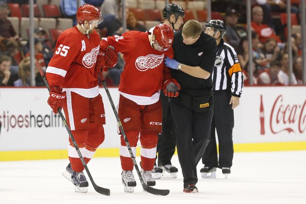 Detroit Red Wings left wing Tomas Tatar (21), of Slovakia, is helped off the ice by Niklas Kronwall (55) and athletic trainer Piet Van Zant in the third period of a NHL preseason hockey game against the Pittsburgh Penguins in Detroit Wednesday, Oct. 1, 2014. (AP Photo/Paul Sancya)