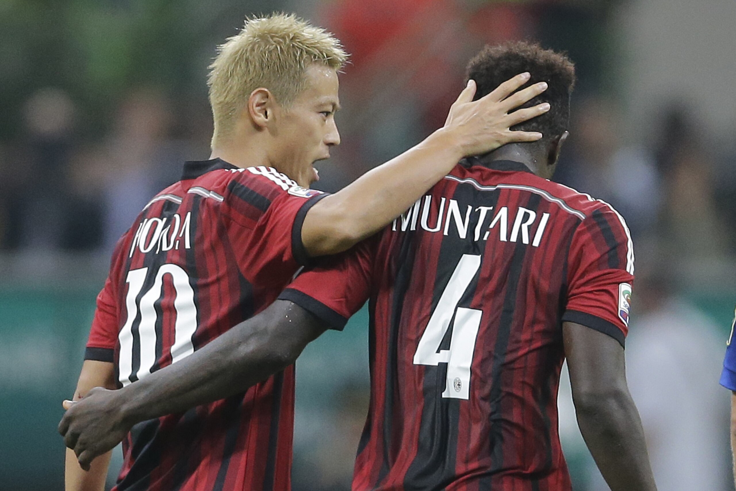 AC Milan's Keisuke Honda, left, celebrates with his teammate Sulley Muntari after scoring during the Serie A soccer match between AC Milan and Chievo at the San Siro stadium in Milan, Italy, Saturday, Oct. 4, 2014. (AP Photo/Antonio Calanni)
