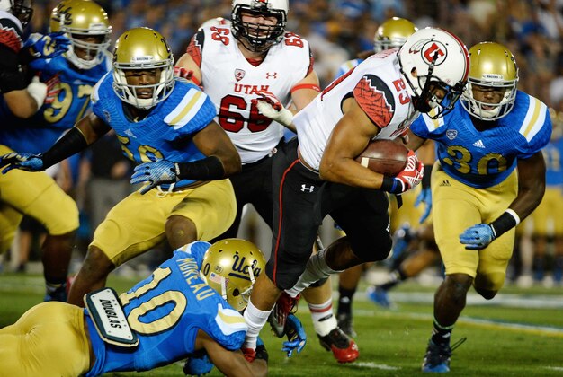 Oct 4, 2014; Pasadena, CA, USA; Utah Utes running back Devontae Booker (23) gains five yards on a first quarter carry as he is tripped up by UCLA Bruins defensive back Fabian Moreau (10) at Rose Bowl. Mandatory Credit: Robert Hanashiro-USA TODAY Sports