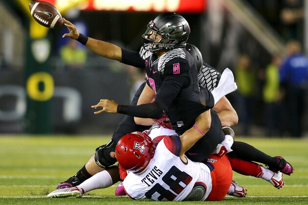 EUGENE, OR - OCTOBER 02: Quarterback Marcus Mariota #8 of the Oregon Ducks pitches the ball while being tackled by Jared Tevis #38 of the Arizona Wildcats at Autzen Stadium on October 2, 2014 in Eugene, Oregon. (Photo by Jonathan Ferrey/Getty Images)