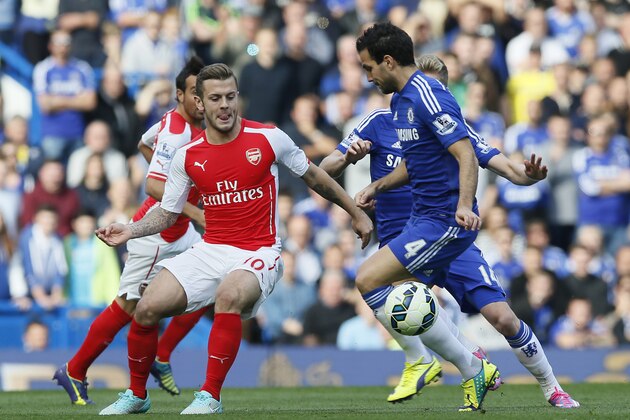 Arsenal's Jack Wilshere, left, passes the ball under pressure from Chelsea's Cesc Fabregas during their English Premier League soccer match between Chelsea and Arsenal at Stamford Bridge stadium in London Sunday, Oct. 5, 2014. (AP Photo/Alastair Grant)