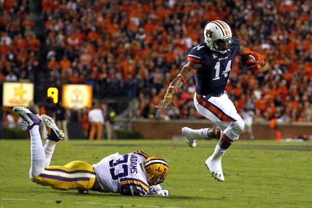 Auburn quarterback Nick Marshall (14) jumps over LSU safety Jamal Adams (33) as he carries the ball during the first half of an NCAA college football game on Saturday, Oct. 4, 2014, in Auburn, Ala. (AP Photo/Butch Dill)