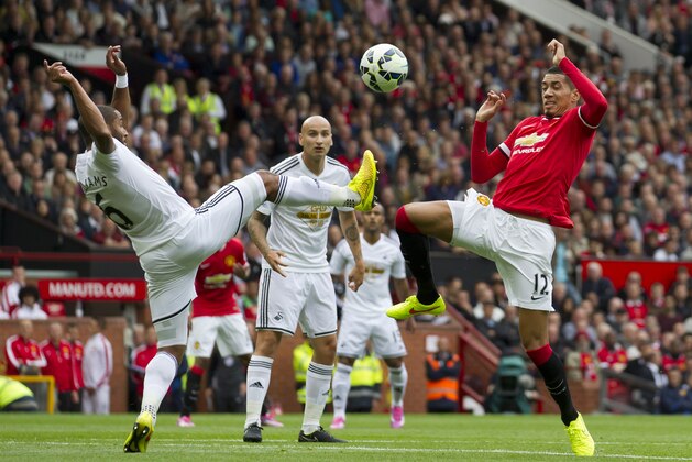 Manchester United's Chris Smalling, right, fights for the ball against Swansea City's Ashley Williams during their English Premier League soccer match at Old Trafford Stadium, Manchester, England, Saturday Aug. 16, 2014. (AP Photo/Jon Super)