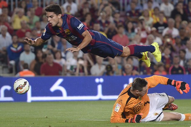 FC Barcelona's Marc Bartra, left, duels for the ball against Elche's goalkeeper Przemyslaw Tyton during a Spanish La Liga soccer match at the Camp Nou stadium in Barcelona, Spain, Sunday, Aug. 24, 2014. (AP Photo/Manu Fernandez)