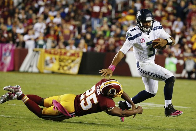 Russell Wilson, de los Seahawks de Seattle, elude a Ryan Clark, safety de los Redskins de Washington, durante el partido del lunes 6 de octubre de 2014 (AP Foto/Alex Brandon)