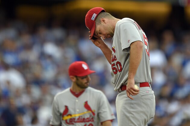 St. Louis Cardinals starting pitcher Adam Wainwright, right, wipes his face after walking Los Angeles Dodgers' Adrian Gonzalez in the fourth inning in Game 1 of baseball's NL Division Series in Los Angeles, Friday, Oct. 3, 2014. (AP Photo/Mark J. Terrill)