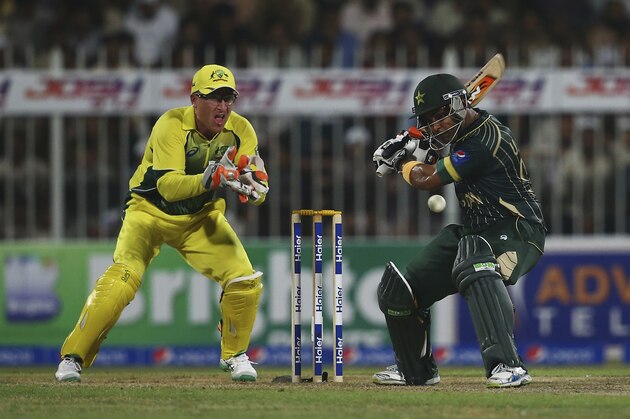 SHARJAH, UNITED ARAB EMIRATES - OCTOBER 07: Umar Akmal of Pakistan bats as Brad Haddin of Australia looks on during the first match of the one day international series between Australia and Pakistan at Sharjah Cricket Stadium on October 7, 2014 in Sharjah, United Arab Emirates.  (Photo by Francois Nel/Getty Images)