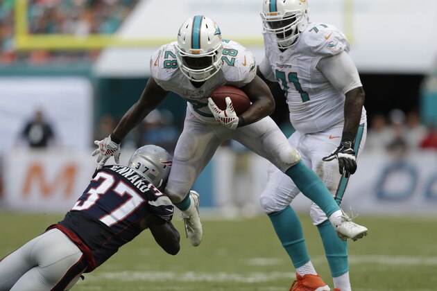Miami Dolphins running back Knowshon Moreno (28) avoids a tackle by New England Patriots cornerback Alfonzo Dennard (37) during the second half of an NFL football game, in Miami Gardens, Fla., Sunday Sept. 7, 2014. (AP Photo/Wilfredo Lee)