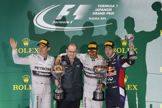 Mercedes driver Lewis Hamilton, second from right, of Britain celebrates with second placer teammate Nico Rosberg, left, and third placer Red Bull Racing driver Sebastian Vettel of Germany during an award ceremony after winning the Japanese Formula One Grand Prix at the Suzuka Circuit in Suzuka, central Japan, Sunday, Oct. 5, 2014. Man second from left is Peter Hodgkinson, head of build at Mercedes Factory. (AP Photo/Shuji Kajiyama)