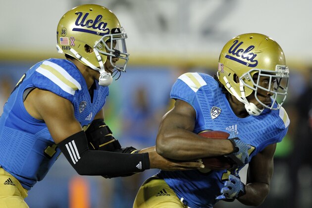 UCLA quarterback Brett Hundley, left, hands off to UCLA running back Paul Perkins, right, during the first half of an NCAA college football game Saturday, Oct. 4, 2014, in Pasadena, Calif.  (AP Photo/Alex Gallardo)