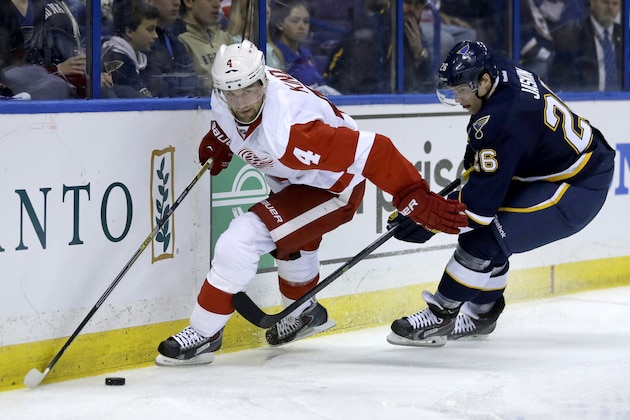 Detroit Red Wings' Jakub Kindl, left, of the Czech Republic, and St. Louis Blues' Dmitrij Jaskin, of Russia, chase a loose puck during the second period of an NHL hockey game Sunday, April 13, 2014, in St. Louis. (AP Photo/Jeff Roberson)