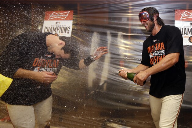 San Francisco Giants Buster Posey gets doused with alcohol by teammate Madison Bumgarner, right, in the locker room after the Giants beat the Washington Nationals 3-2 to win Game 4 of baseball's NL Division Series in San Francisco, Tuesday, Oct. 7, 2014. (AP Photo/Ben Margot)