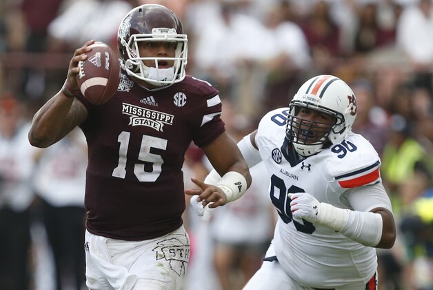 Mississippi State quarterback Dak Prescott (15) is pursued by Auburn defensive lineman Gabe Wright (90) during the first half of an NCAA college football game in Starkville, Miss., Saturday, Oct 11, 2014.  (AP Photo/Rogelio V. Solis)