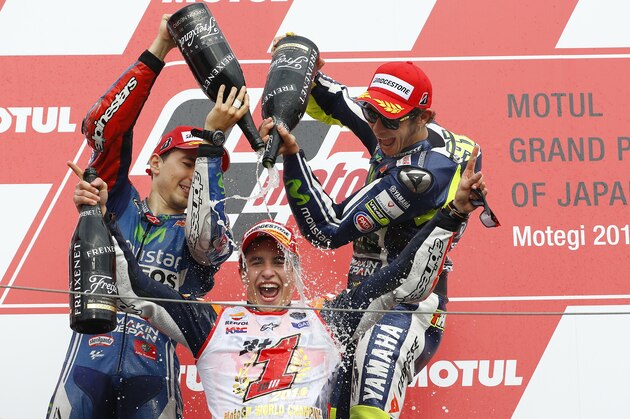 Spain's Marc Marquez is sprayed champagne by race winner and compatriot Jorge Lorenzo, left, and third-placed Valentino Rossi of Italy, right, during the awarding ceremony of Japanese Motorcycle Grand Prix at Twin Ring Motegi circuit in Motegi, north of Tokyo, Japan, Sunday, Oct. 12, 2014. Honda rider Marquez defended his MotoGP championship on Sunday when he finished second in the Grand Prix of Japan behind compatriot Lorenzo. (AP Photo/Shizuo Kambayashi)