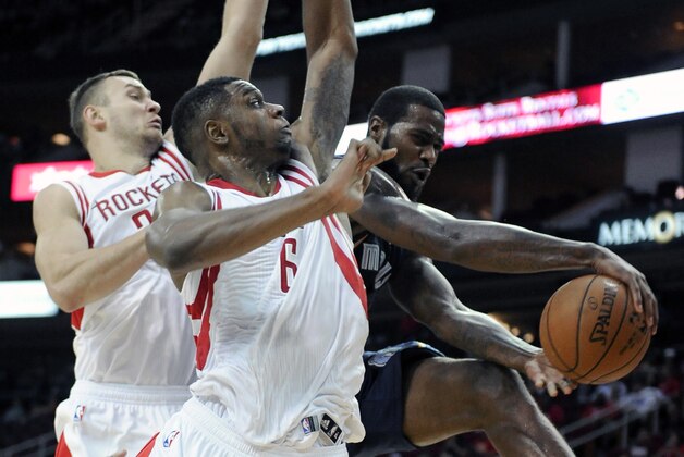 Memphis Grizzlies' Earl Clark, right, passes the ball around Houston Rockets Donatas Motiejunas, left, and Kostas Papanikolaou in the second half of an NBA exhibition basketball game Thursday, Oct. 9, 2014, in Houston. (AP Photo/Pat Sullivan)